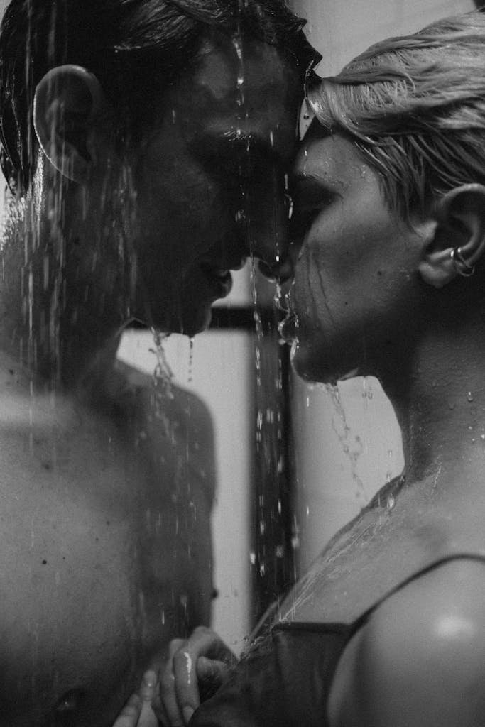 A romantic moment of a couple sharing an intimate shower, captured in black and white.