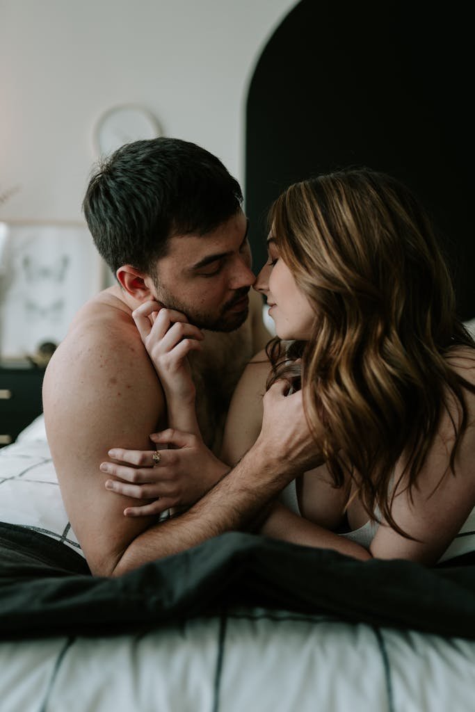 A young couple sharing a tender moment of intimacy in a cozy bedroom setting.